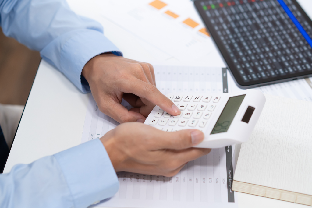 Persoană care folosește un calculator pentru a calcula costurile de transport, reprezentând analiza ofertelor și strategiile de preț.